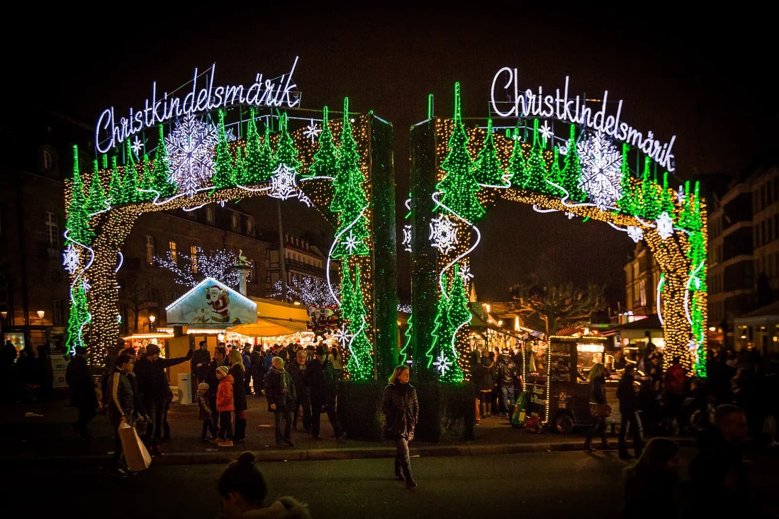 Šviečiantys Strasbūro kalėdinės mugės „Christkindelsmärik“ vartai ir lankytojai vakare