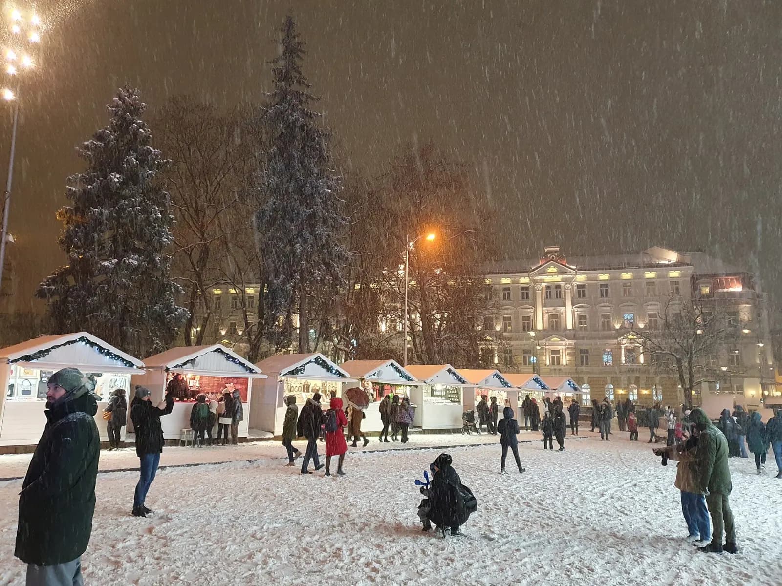 Kalėdinės mugės kiosketai Katedros aikštėje, tarp jų vaikšto žmonės